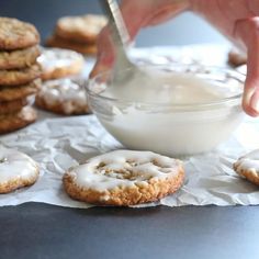 a person dipping icing onto some cookies