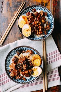 two bowls filled with food sitting on top of a table next to chopsticks