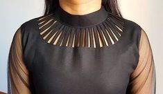 a woman wearing a black top with sheer sleeves and gold details on the neckline