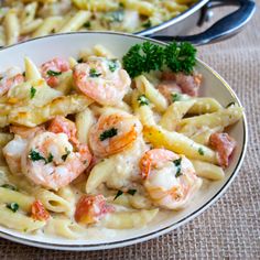 two bowls filled with pasta and shrimp on top of a table