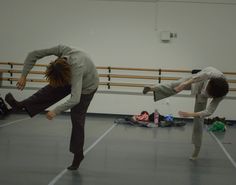 two people doing tricks in an indoor dance studio while one person holds his leg up to the floor