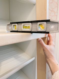 a person is holding two lights in front of a refrigerator door that are both yellow and white