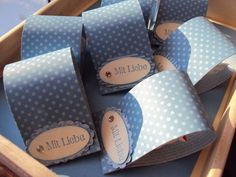 blue and white polka dot gift bags in a wooden box with name tags on them