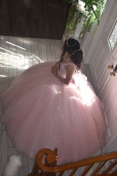 a woman in a pink ball gown is sitting on a chair and looking into the mirror