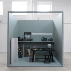 an office cubicle with a desk and chair in the center, surrounded by white walls