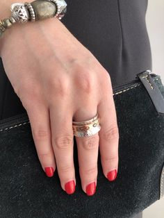 a woman's hand with two rings on her finger and a black purse behind her