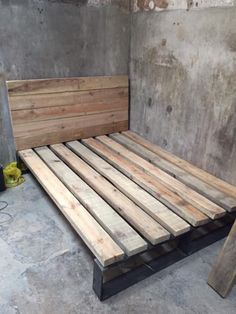 a bed made out of wooden pallets in a room with concrete walls and flooring