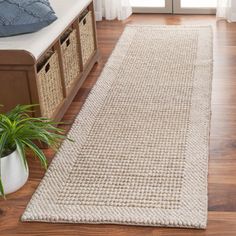 a large white rug on top of a hard wood floor next to a wooden bench