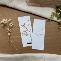 two bookmarks sitting on top of a table next to dried flowers and twine