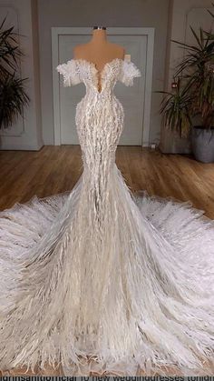 a white wedding dress with feathers on the floor