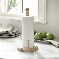 a roll of toilet paper sitting on top of a counter next to some green apples