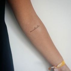 a woman's arm with a small tattoo on the wrist that says, somewhere