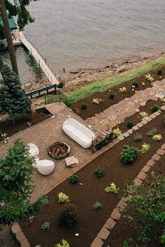 an aerial view of a bathtub in the middle of a garden next to water