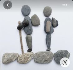 some rocks and a wooden stick on a white surface with the number three in it