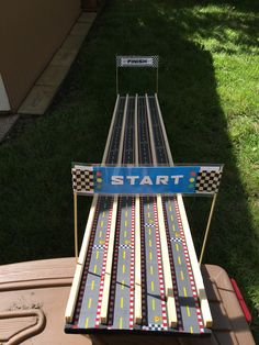 a toy track sitting on top of a wooden table in the grass next to a building