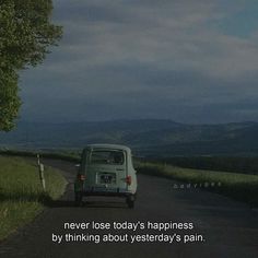 a small van driving down a road next to a lush green hillside under a cloudy sky