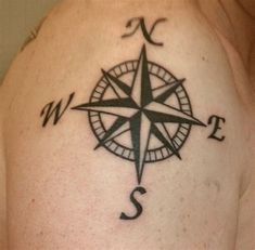 a man's shoulder with a compass tattoo on his left arm and the letter s in black ink