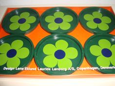 six green and blue flower plates sitting on top of an orange tray with white writing