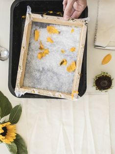 a person is holding a tray with yellow flowers on it and some napkins next to them