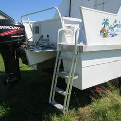 a white boat sitting on top of a grass covered field next to a motorboat