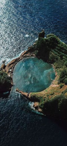 an island in the middle of the ocean surrounded by land and water with trees on it