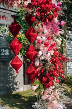 red paper umbrellas hanging from the side of a building with pink and white flowers