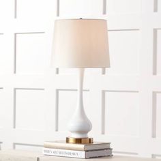 a white table lamp sitting on top of a stack of books