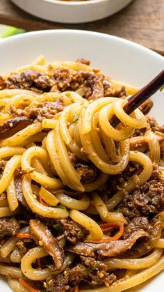 a white bowl filled with noodles and meat