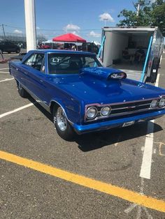 a blue car parked in a parking lot next to a red and white umbrella on top of it