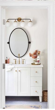 a bathroom vanity with a round mirror above it and gold faucets on the wall