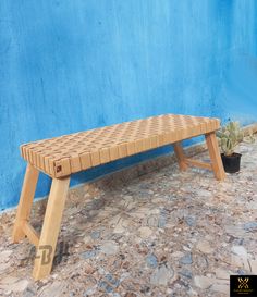 a wooden bench sitting in front of a blue wall next to a potted plant