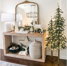 a christmas tree and other decorations on a shelf in a living room with a mirror