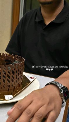 a man sitting at a table in front of a chocolate cake