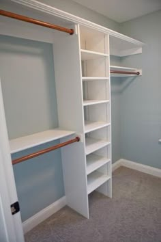 an empty walk in closet with white shelving and copper rails on the door handles