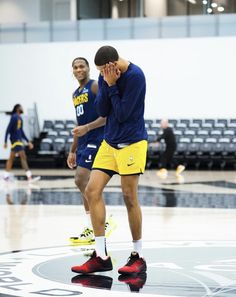 two basketball players are standing on the court with their hands to their face and one is covering his eyes