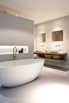 a large white bathtub sitting in the middle of a bathroom next to two sinks