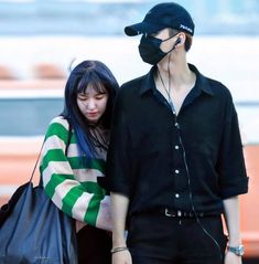 a young man and woman walking together with ear phones in their ears, wearing face masks