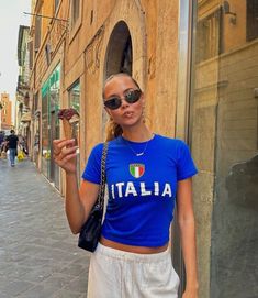 a woman is standing on the street eating food