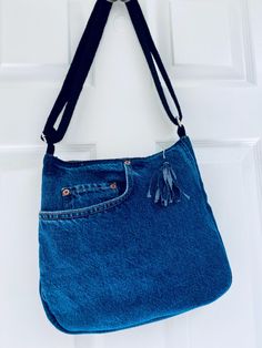 a blue purse hanging on a white door with a black ribbon around the strap and tassel