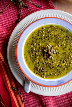 a white bowl filled with green soup sitting on top of a red and yellow cloth