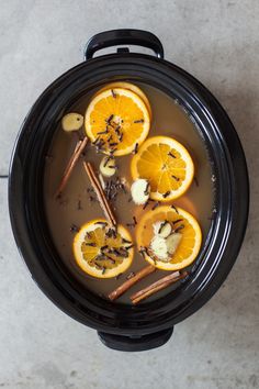 an overhead view of a crock pot filled with orange slices and cinnamon sticks