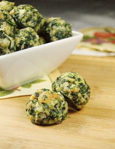 broccoli balls are sitting on a cutting board next to a bowl of food