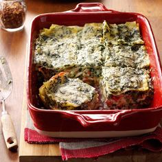 a casserole dish with spinach and cheese in it on a wooden table