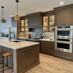 a large kitchen with an island, stove and oven in the center is surrounded by wooden flooring