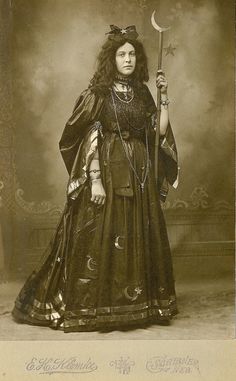 an old fashion photo of a woman dressed in medieval clothing and holding a staff with the moon above her head