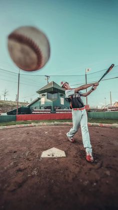 a man swinging a baseball bat at a ball on the field in front of him