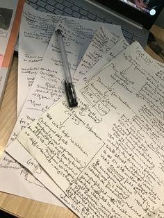 several pieces of paper with writing on them next to a laptop