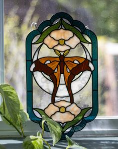 a close up of a stained glass window with a plant in front of the window