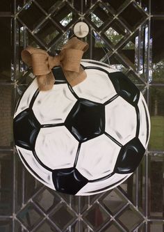 a black and white soccer ball with a bow hanging on a fence behind a chain link gate