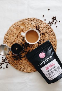 a cup of coffee sitting on top of a table next to a bag of coffee beans